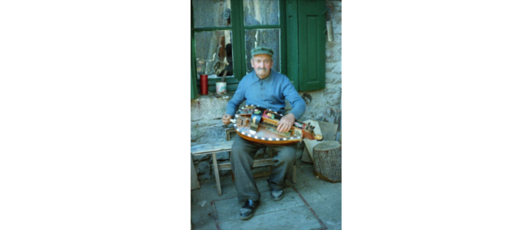Ppapy qui joue de la vielle à roue devant sa maison